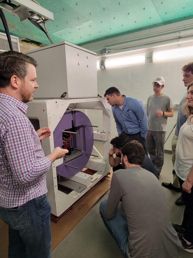 Graduate Students standing next to a machine